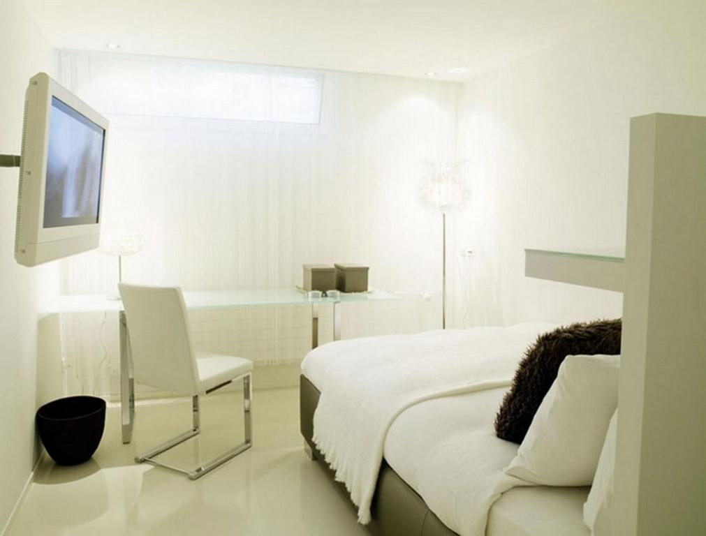 a white bedroom with a bed and a chair and a tv at VISIONAPARTMENTS Binzmühlestrasse 48 - contactless check-in in Zürich