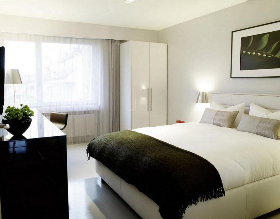 a white bedroom with a large bed and a window at VISIONAPARTMENTS Binzmühlestrasse 48 - contactless check-in in Zürich