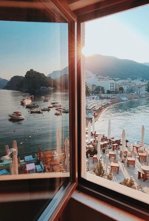 a window with a view of a beach and the water at Apartments First Line in Petrovac na Moru