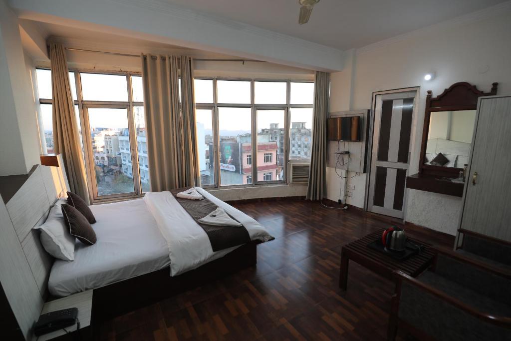 una camera d'albergo con un letto e ampie finestre di Hotel Neelkanth Katra Managed By Mahadev Hotel and Resorts a Katra