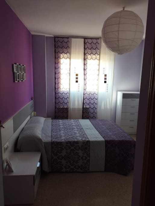 1 dormitorio con cama y pared púrpura en La casa de Ainhoa, en Teruel