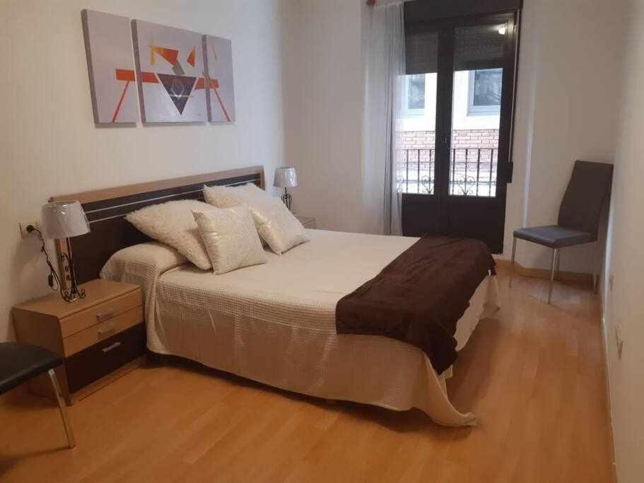 una camera con un grande letto e una sedia di Apartamento San Andrés a Teruel