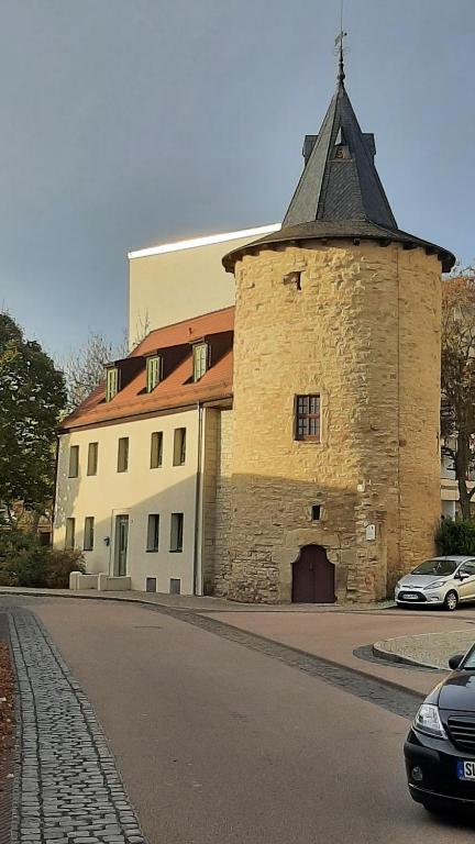 a large stone building with a tower on a street at Gästehaus Am Hasenturm in Bernburg