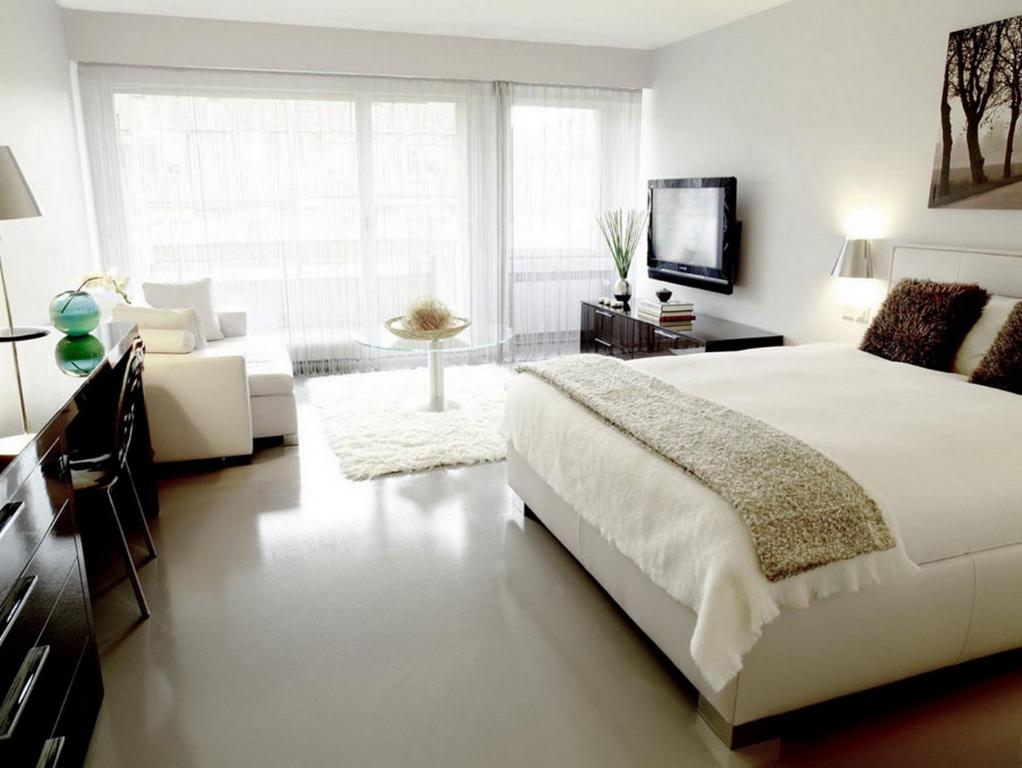 a white bedroom with a bed and a living room at VISIONAPARTMENTS Binzmühlestrasse 48 - contactless check-in in Zürich