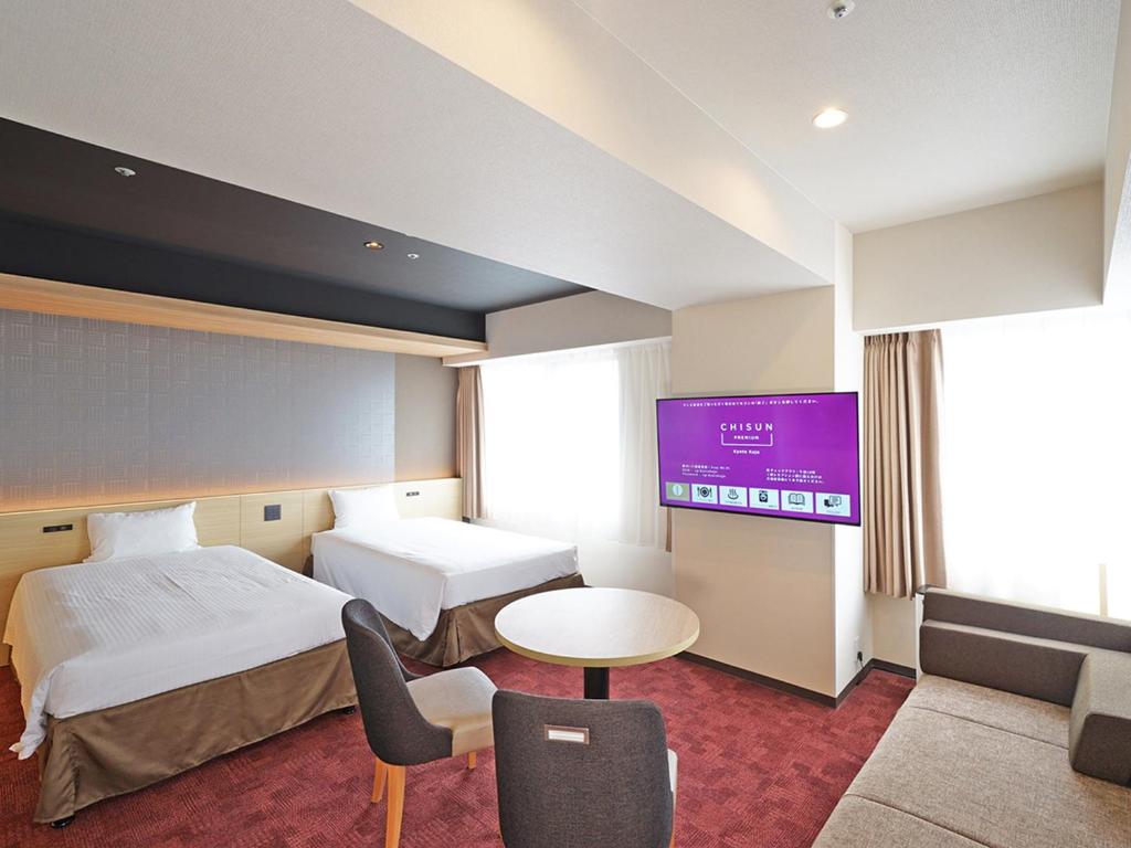 a hotel room with two beds and a flat screen tv at CHISUN PREMIUM Kyoto Kujo in Kyoto