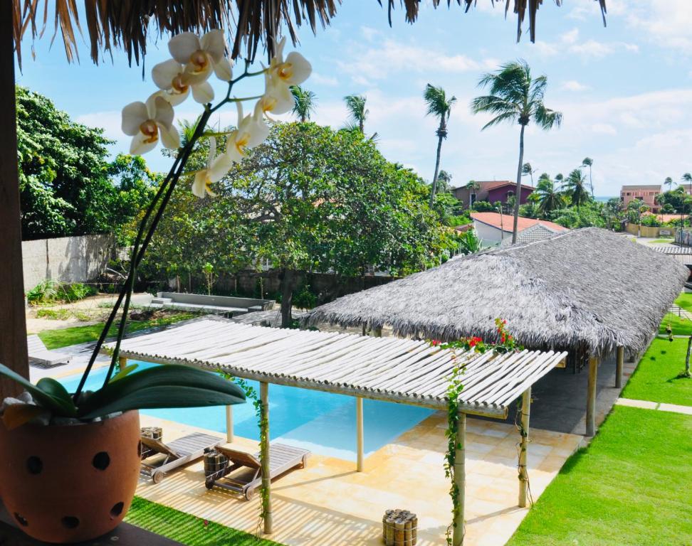 a resort with a pool and a straw umbrella at Pousada Casa Caju Bangalows in Cumbuco