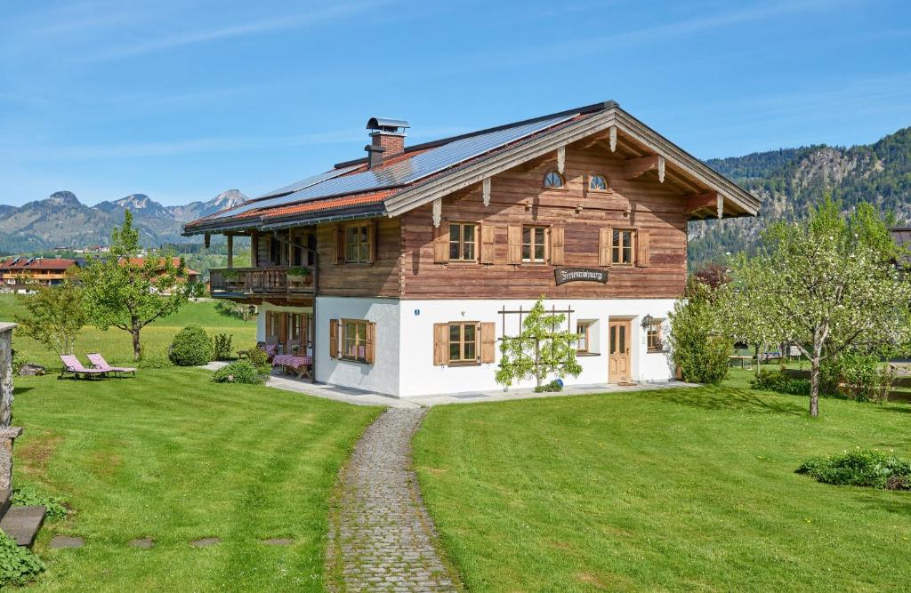 a large wooden house with a green yard at Chalet Menkenhof in Reit im Winkl