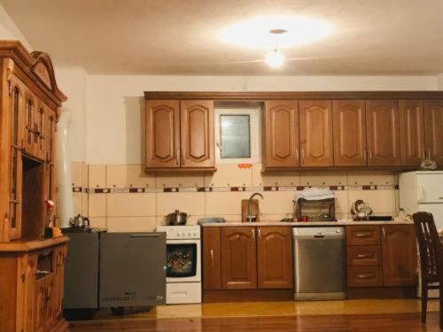 a large kitchen with wooden cabinets and appliances at Dedushi Guesthouse &Wood cabins-Camping place in Gusinje