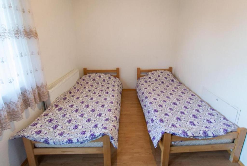 two twin beds in a room with a window at Dedushi Guesthouse &Wood cabins-Camping place in Gusinje