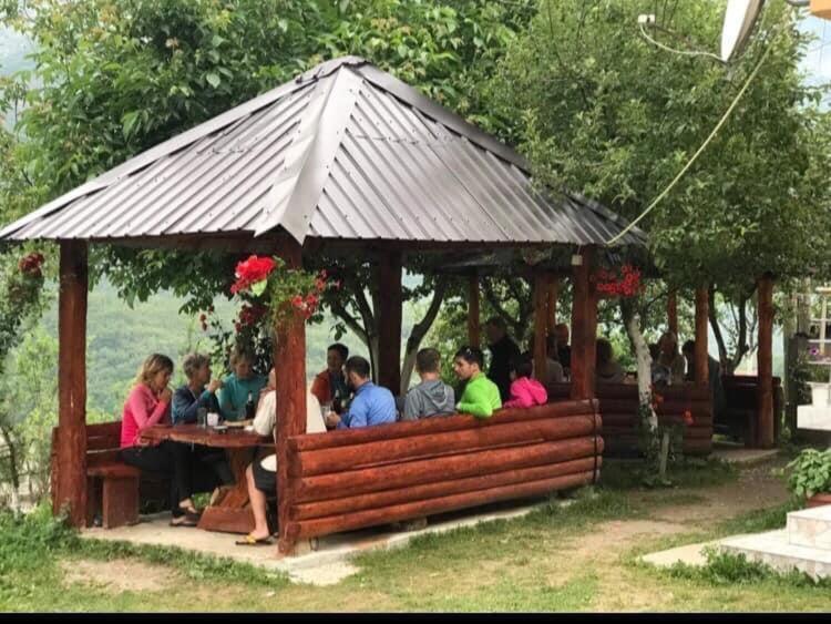 a group of people sitting in a gazebo at Dedushi Guesthouse &Wood cabins-Camping place in Gusinje