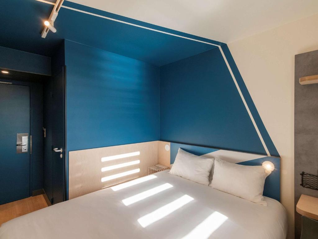 a bedroom with a large bed with a blue wall at ibis budget Lyon Centre Confluence in Lyon