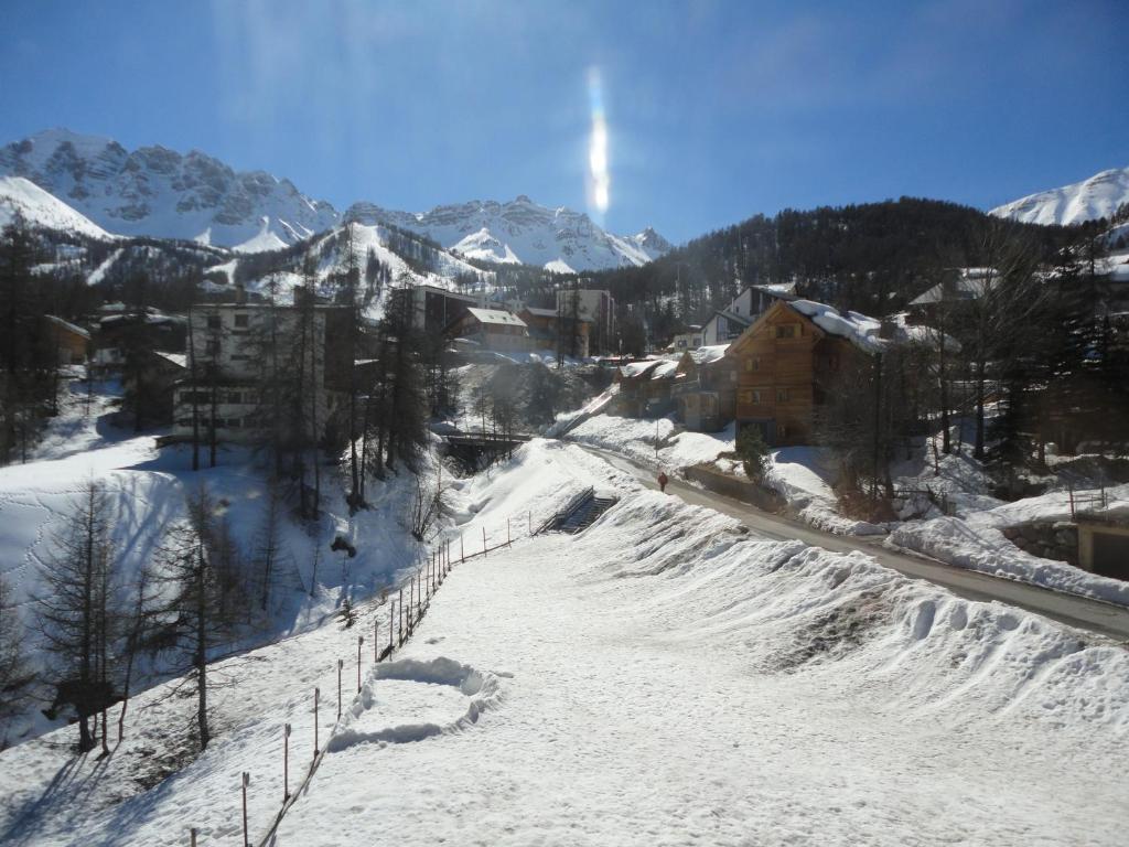 un villaggio ricoperto di neve con recinzione e montagne di Les Carlines a Vars