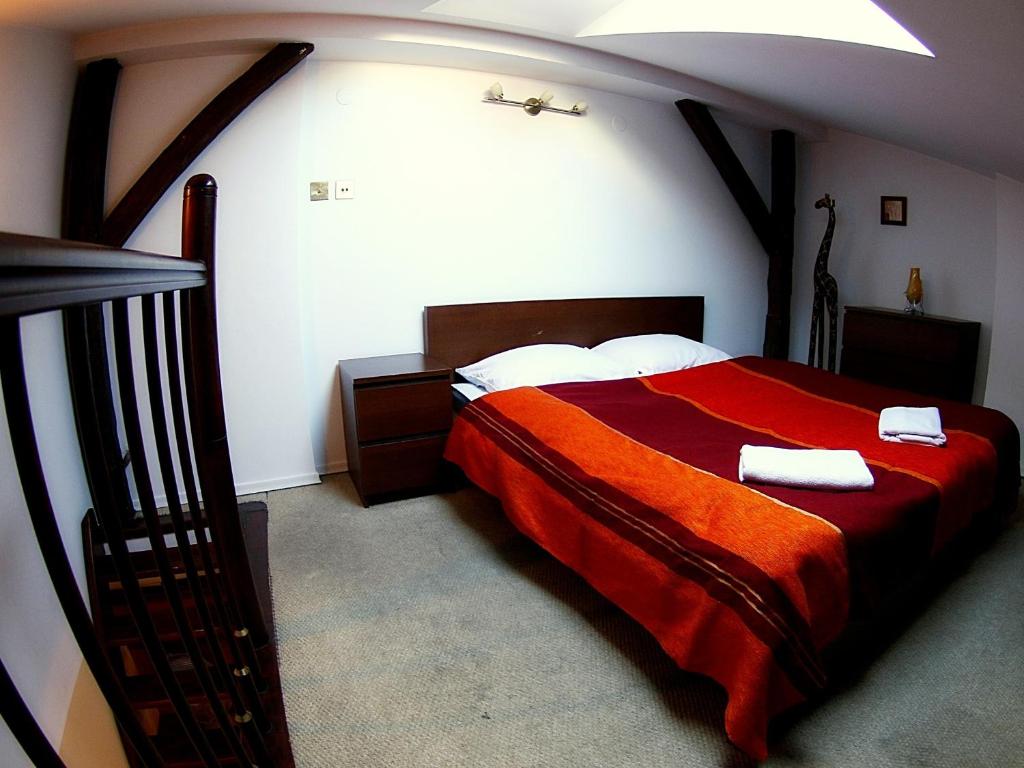 a bedroom with a red bed with two towels on it at Skałka Krakow Apartments in Krakow