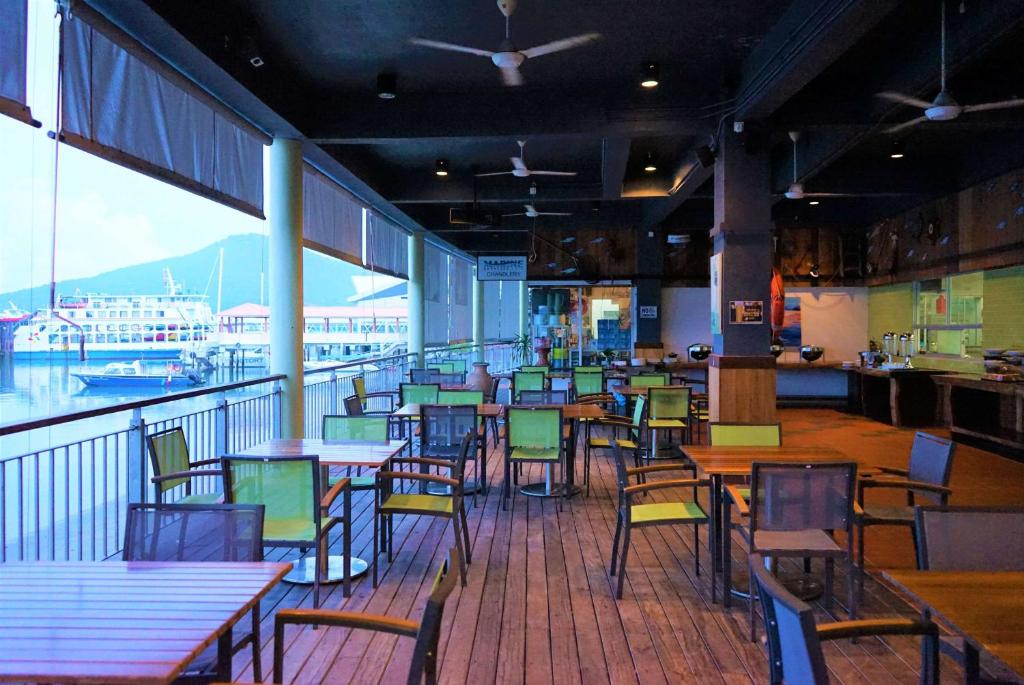 un restaurante con mesas y sillas y vistas a un barco en Ramada by Wyndham Langkawi Marina en Kuah