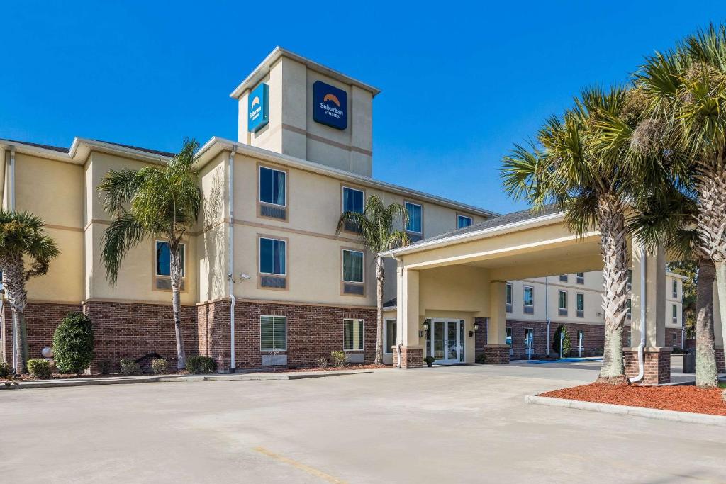 ein Hotel mit Palmen vor einem Gebäude in der Unterkunft Suburban Studios Berwick - Morgan City in Berwick