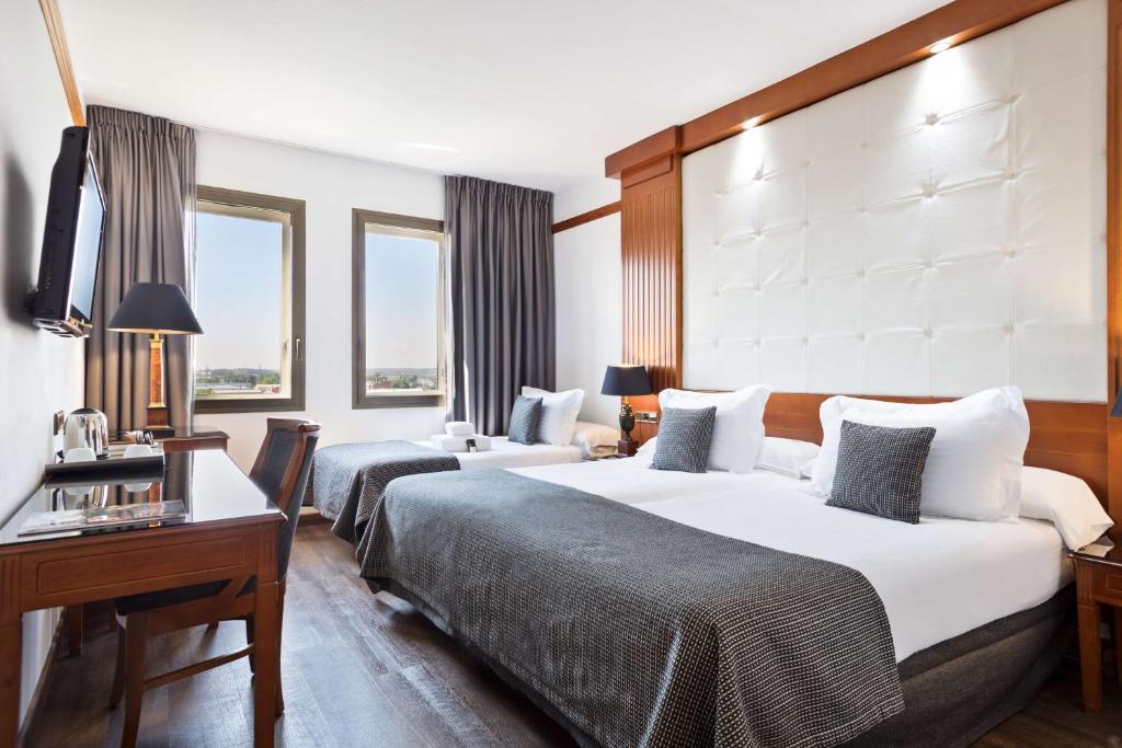 um quarto de hotel com duas camas e uma secretária em Best Western Premier CMC Girona em Girona