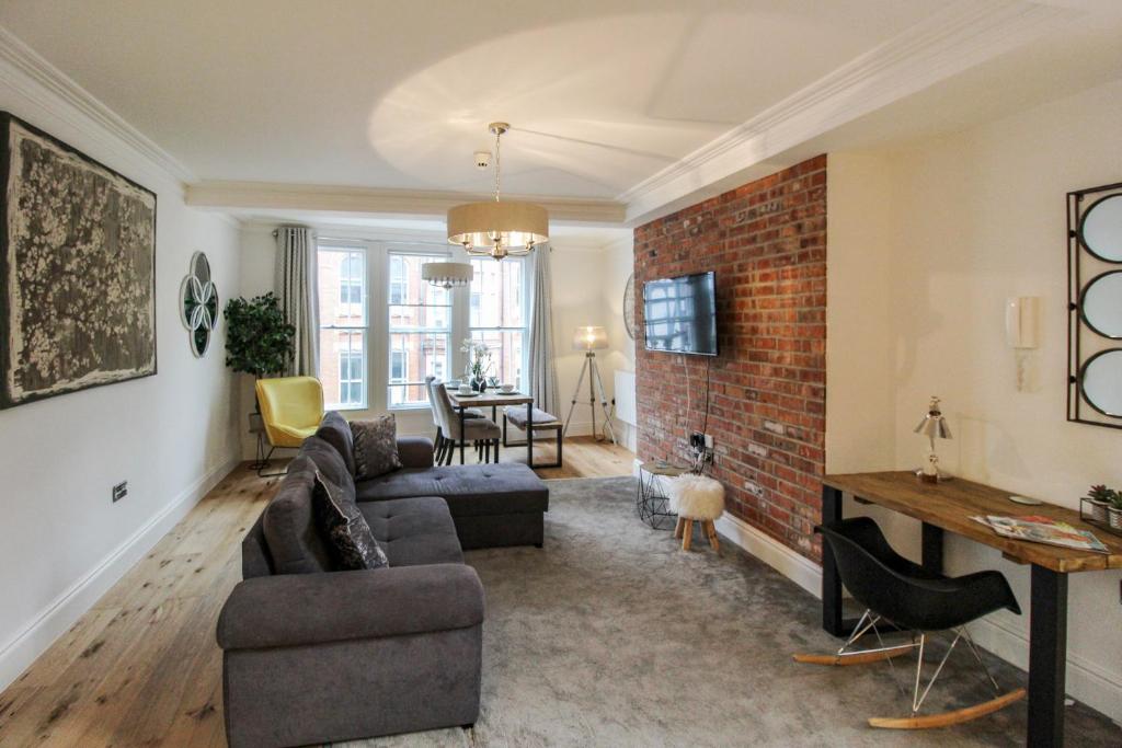 a living room with a couch and a brick wall at Spacious, Elegant City Centre Apartment with FREE WIFI in Nottingham