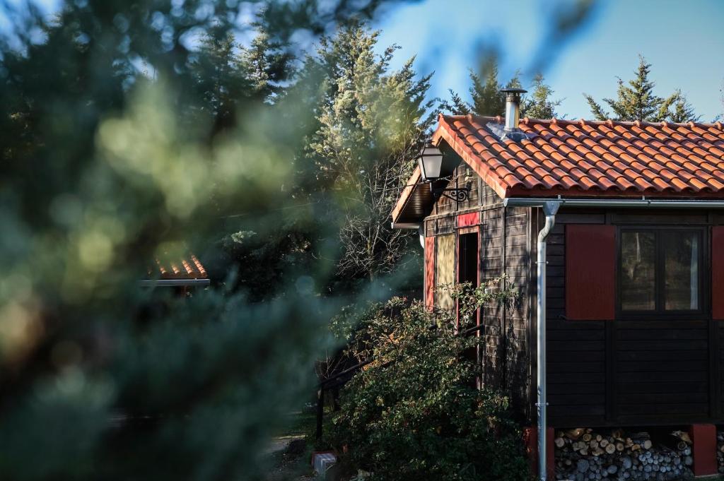 ein Haus mit einem roten Kacheldach und Bäumen in der Unterkunft Casa Rural La Canadiense Log Cabin in Buenache de la Sierra