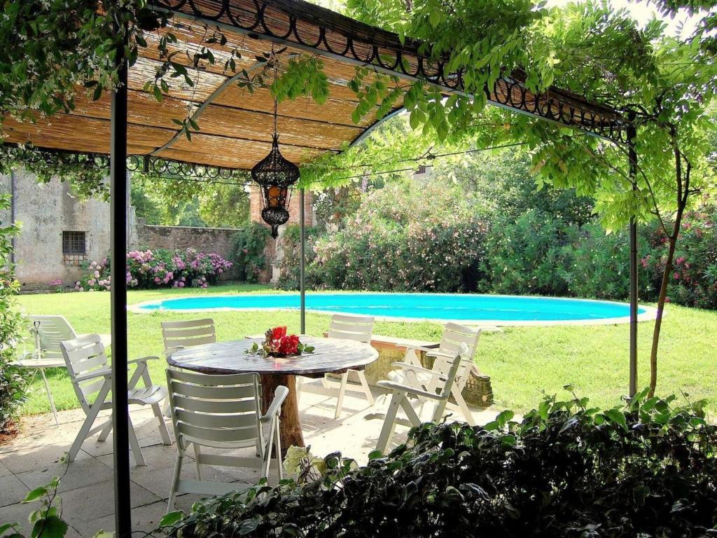 un tavolo e sedie sotto un pergolato accanto alla piscina di Historic Venetian Style Castle in Piombino Dese with Pool a Piombino Dese