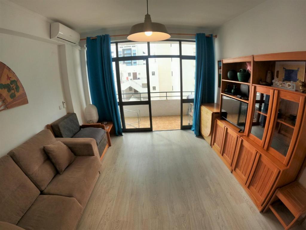 uma sala de estar com um sofá e uma grande janela em Algarve, modern T1 apartment with balcony, Quarteira em Quarteira