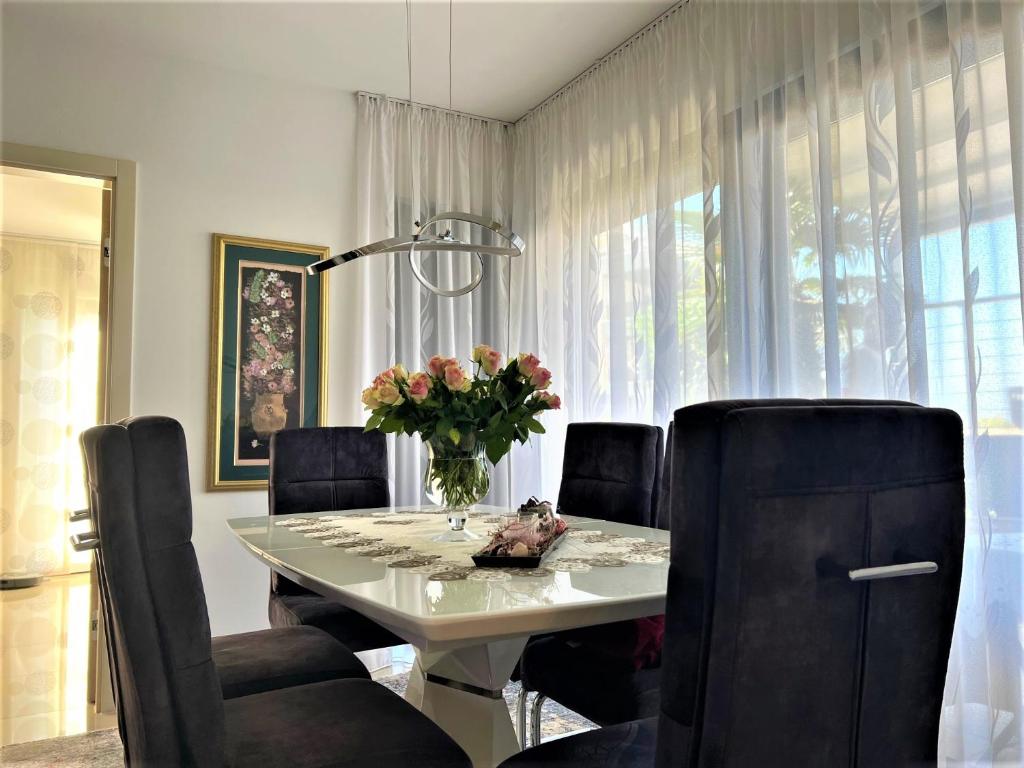 une table à manger avec des chaises et un vase de fleurs dans l'établissement Apartment Lena, à Medulin