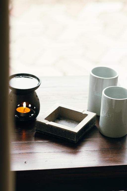 a table with two cups and a candle and a box at Salt Mirissa in Mirissa