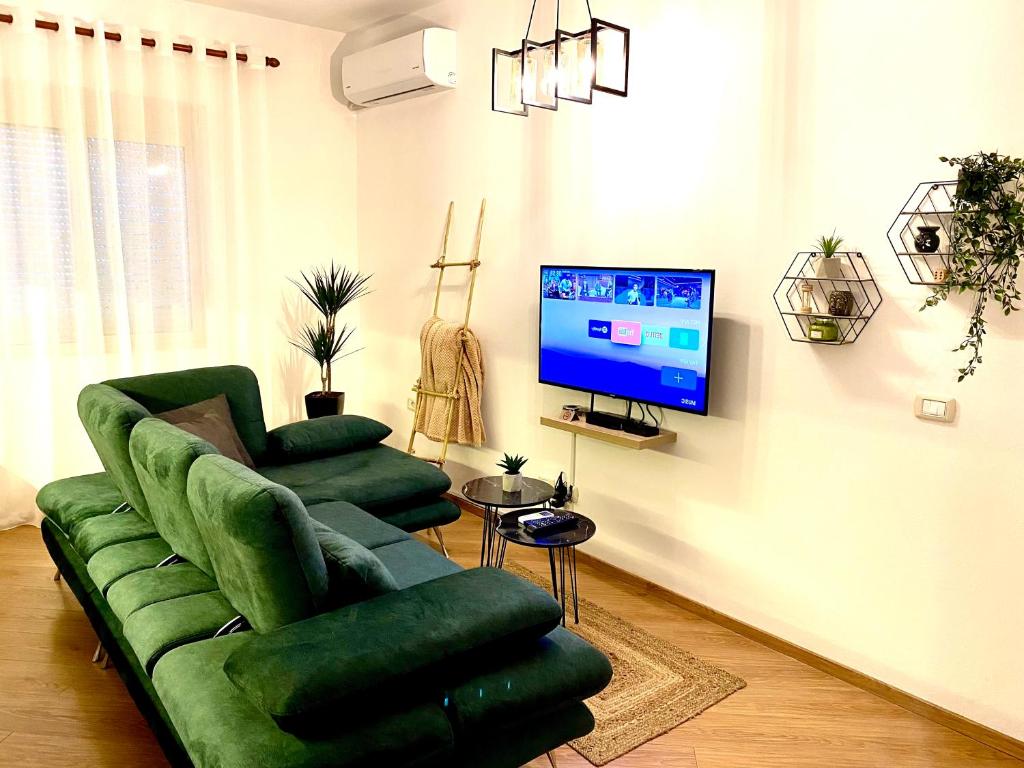 sala de estar con sofá verde y TV en Luxury Apartments in City Center, en Durrës