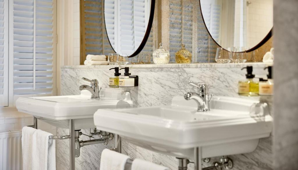 two sinks in a bathroom with mirrors and towels at Pulitzer Amsterdam in Amsterdam