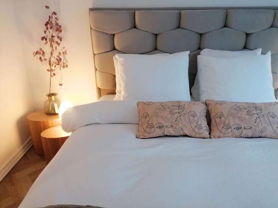 een slaapkamer met een groot bed met witte lakens en kussens bij Appartement Fernand Namur in Namen