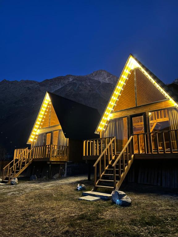 a log cabin with lights on the side of it at Eco cottage Kazbegi in Stepantsminda