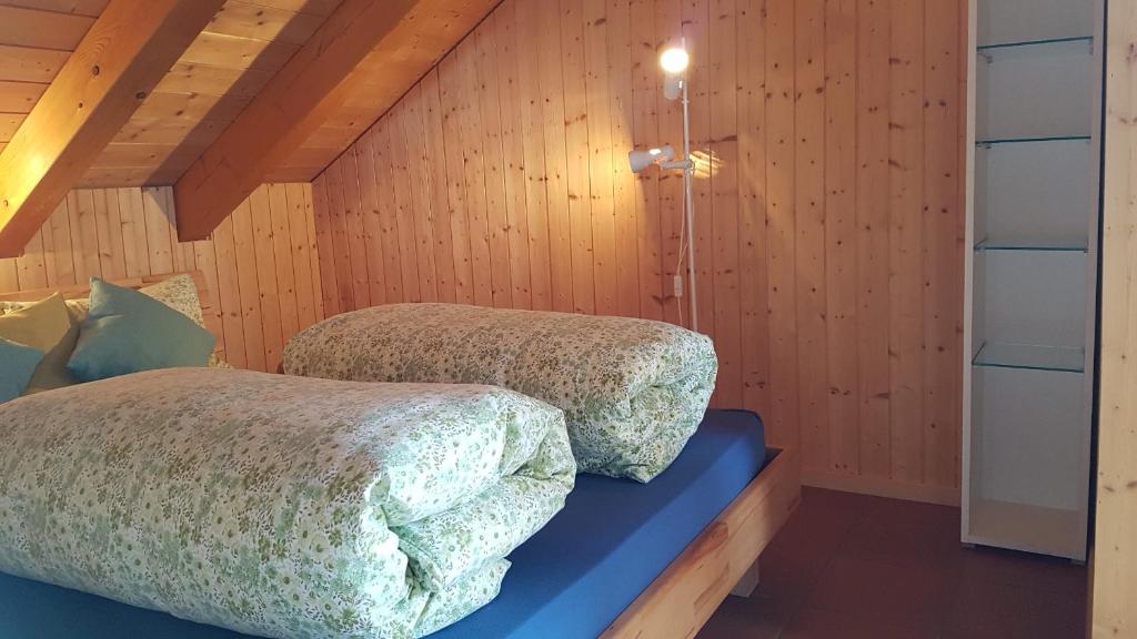 two beds in a room with wooden walls at Schwendihof in Flumserberg