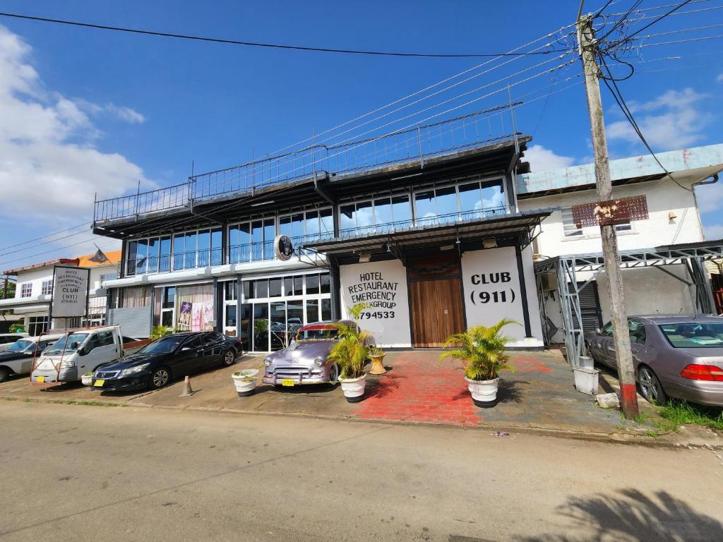 un edificio con coches estacionados frente a él en Hotel Bar Restaurant Emergency 911 STO LK GROUP, en Paramaribo