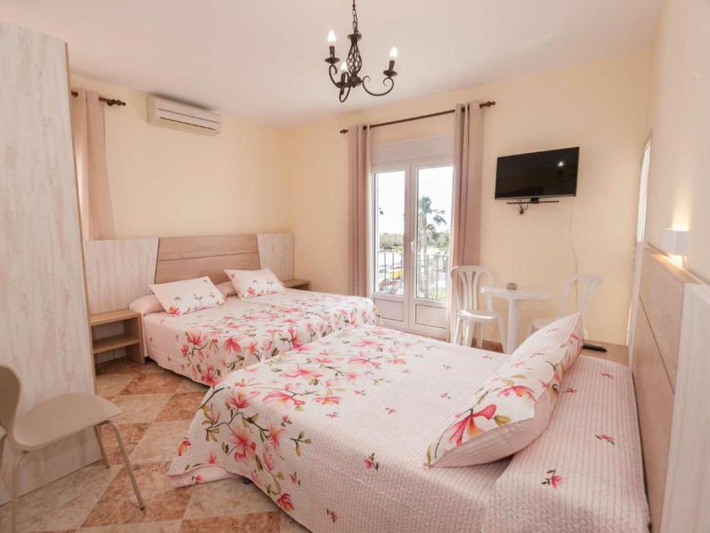 a bedroom with two beds and a table and a tv at Hostal Sonrisa del Mar in Conil de la Frontera