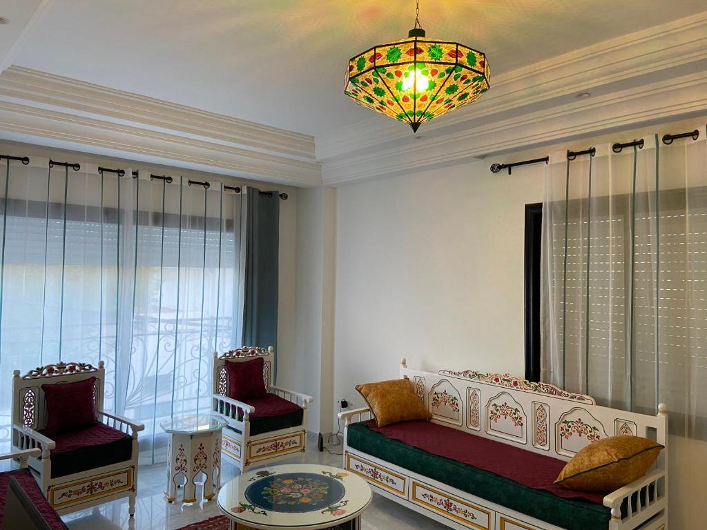 a bedroom with a bed and two chairs and a chandelier at Marsa Authentic Luxury Appart 1 in La Marsa