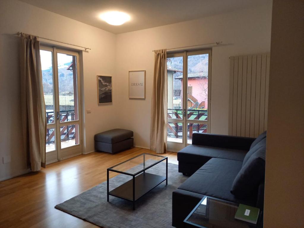 ein Wohnzimmer mit einem Sofa und einem Tisch in der Unterkunft Presolana Home in Castione della Presolana