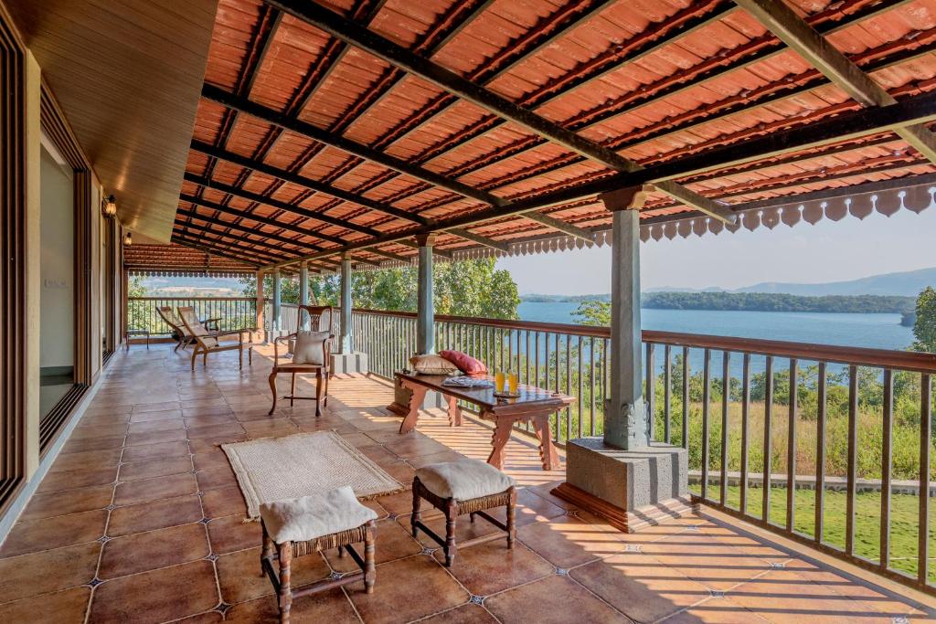 Nethersole Dam的住宿－SaffronStays Anantham, Kamshet - pet-friendly lakefront villa with a huge verandah，带桌椅的带顶棚门廊