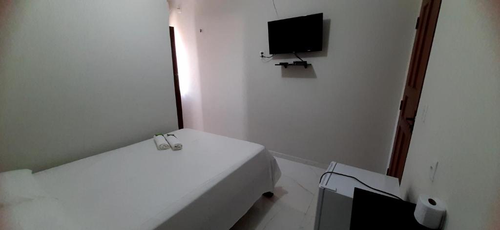 a white room with a bed and a flat screen tv at Pousada Brilho dos Lençóis in Barreirinhas