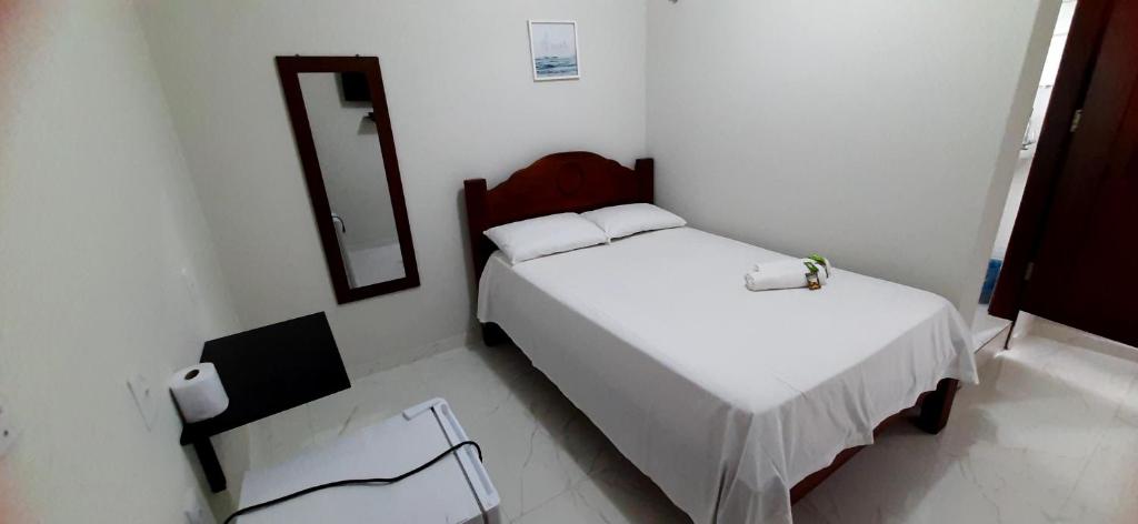 a small white room with two beds and a mirror at Pousada Brilho dos Lençóis in Barreirinhas