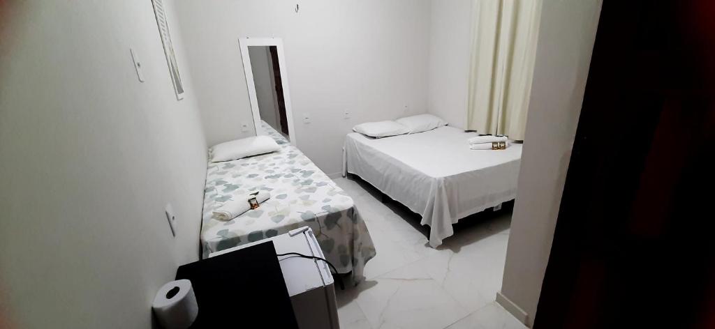 a small white room with a bed and a mirror at Pousada Brilho dos Lençóis in Barreirinhas