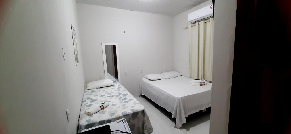 a small white room with a bed and a window at Pousada Brilho dos Lençóis in Barreirinhas