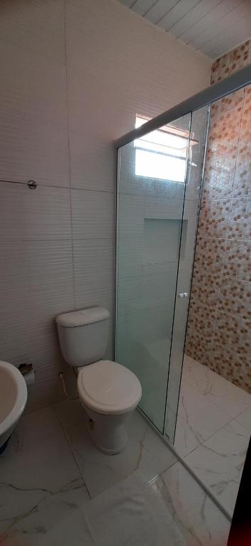 a bathroom with a toilet and a glass shower at Pousada Brilho dos Lençóis in Barreirinhas