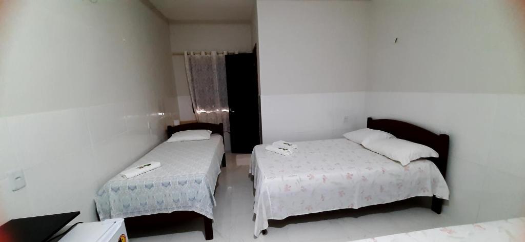a room with two beds in a room with a window at Pousada Brilho dos Lençóis in Barreirinhas