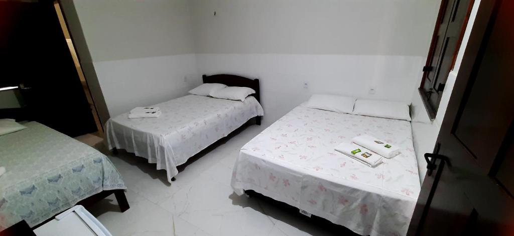 two beds in a room with white walls at Pousada Brilho dos Lençóis in Barreirinhas