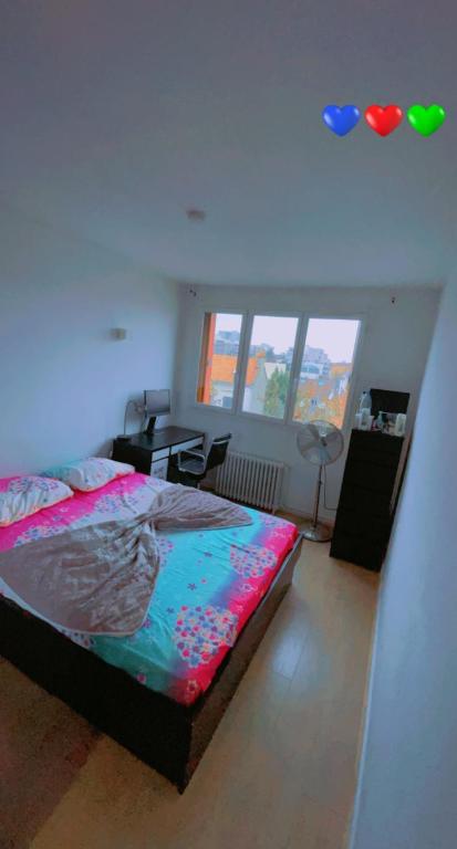 a bedroom with a bed and a desk and windows at Chambre Propre Calme dans un Quartier Pavillonnaire Proche de Paris, La Défense, Les champs Élysées et Toutes Commodités in Nanterre