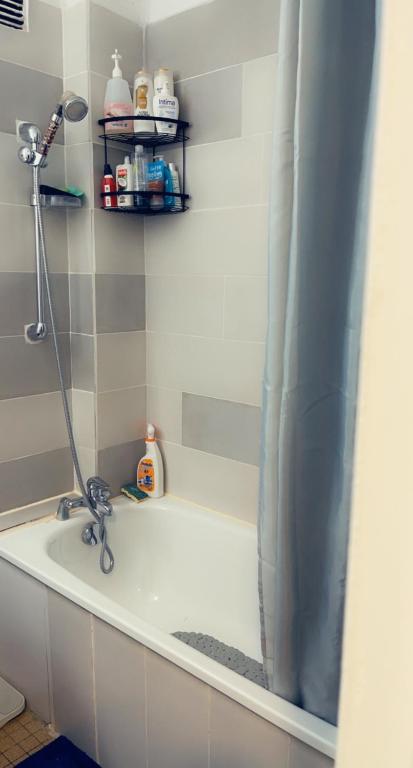 a bath tub with a shower curtain in a bathroom at Chambre Propre Calme dans un Quartier Pavillonnaire Proche de Paris, La Défense, Les champs Élysées et Toutes Commodités in Nanterre