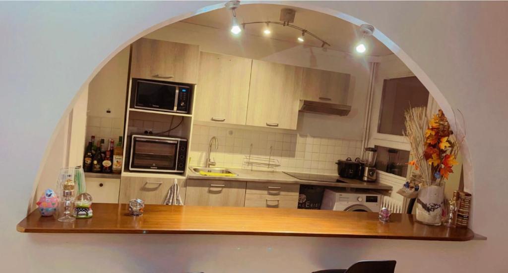 a kitchen with an arch over a wooden counter top at Chambre Propre Calme dans un Quartier Pavillonnaire Proche de Paris, La Défense, Les champs Élysées et Toutes Commodités in Nanterre