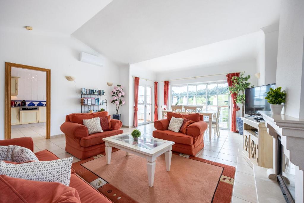 uma sala de estar com cadeiras vermelhas e uma mesa em Casa Ensolarada em Budens