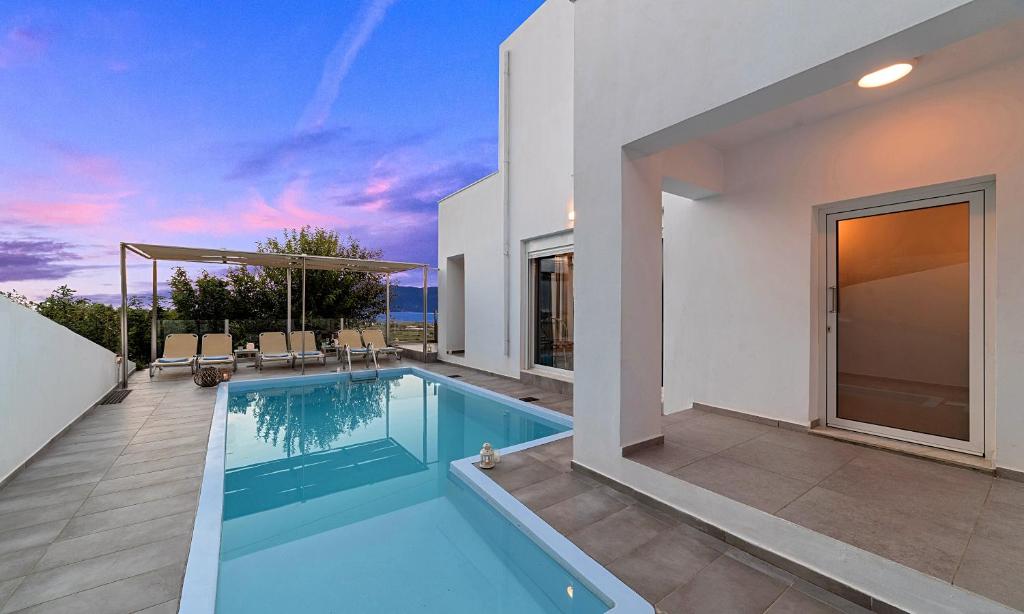 a villa with a swimming pool and a patio at Cretan Sunset Villa Heated Pool in Dhrámia