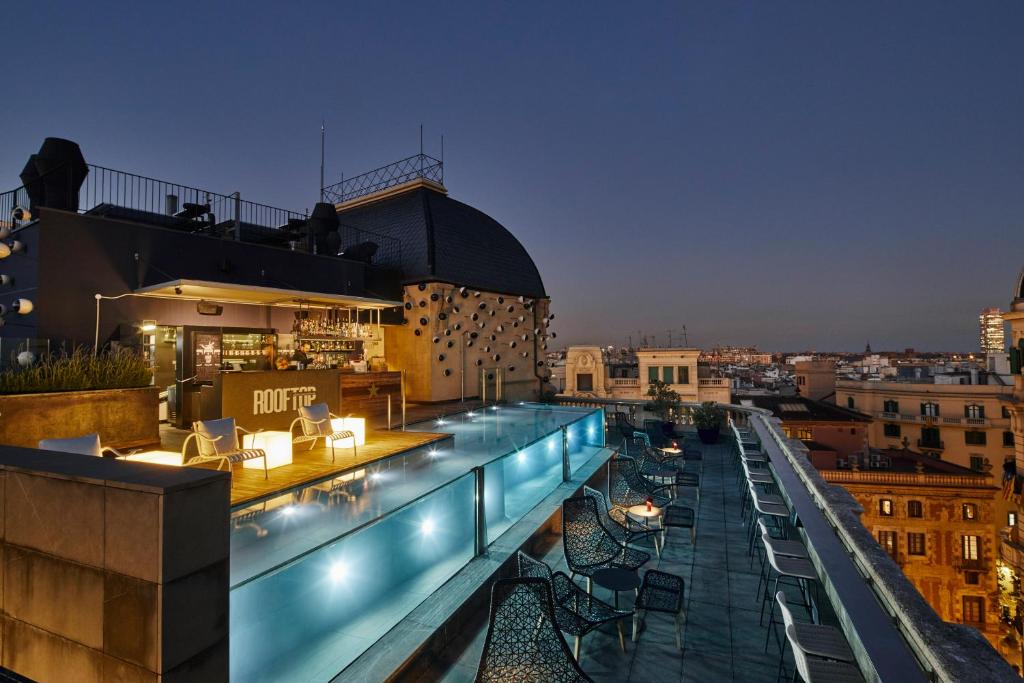 un bar en la azotea con sillas y mesas en un edificio en Ohla Barcelona, en Barcelona