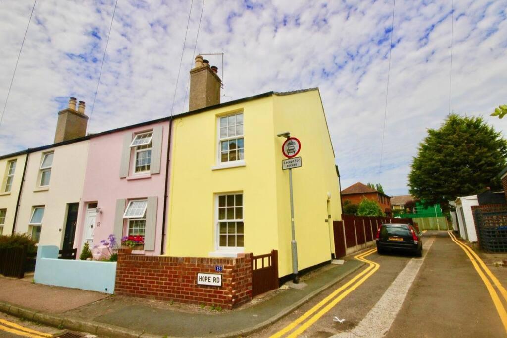 a yellow and pink house on the side of a street at Pebbles in Deal